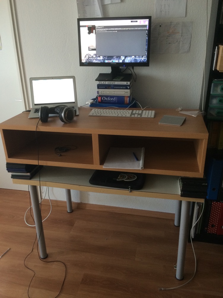 Ein Bild von meinem DIY-Stehschreibtisch. Man nehme: Einen normalen Schreibtisch und stelle da ein IKEA-Regal, auf dem vorher der Fernseher stand drauf. Um die optimale Höhe zu erreichen nutze ich ein paar DVD-Hüllen